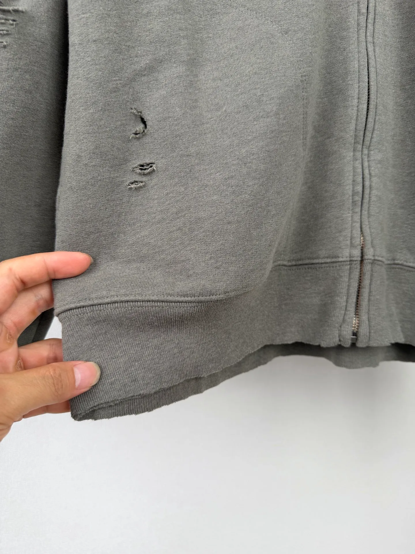 Acne Studios ripped distressed logo zipper sweatshirt jacket Custom dyed 1:1 gray green soft cotton colored cotton sweatshirt material [The surface fabric and terry base are of the same color (the market fabric In Stock has different colors and does not match the original version) The minimum order quantity of the fabric is 2 tons. The pure fabric manufacturing process takes 45 days] Cloud-like touch, delicate softness, comfortable and skin-friendly. It is presented in a pure gray-green tone, which seems to be the elegance after years of precipitation. The front panel is homogeneous and clean fit. The back panel is engraved with the uninhibited soul of Acne Studios. The ingenious integration of hole elements on the black canvas is a deliberate rebellion. It is a break away from the shackles of tradition and is unique in the wave of the trend. Process 1: Using glue printing. The chest printing has been modified three times by the film screen. Use glue liquid paint to print the pattern on the fabric. Bake the fabric to fix the printed pattern. Technique 2: Many parts of the body are worn by pure manual regular positioning. Manual brush marks. Add texture and depth to the surface of clothing to imitate the texture of natural wear. Process 3: The fabrics are washed and have a better hand feel. Not easy to deform, not easy to shrink, not easy to fade, and maintain long-term beauty. Accessories: Customized 1:1 Acne zipper. Customized 1:1 Acne trademark. Version: Loose version. Size: S M L XL